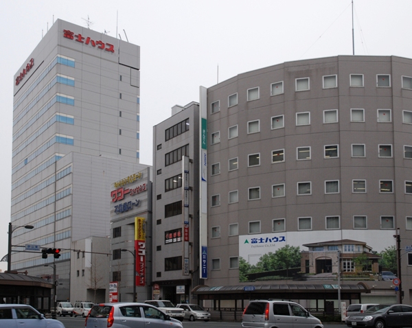 JR浜松駅付近にそびえる富士ハウスの本社ビル（左端）と、付近のビルに掲げられた同社の屋外広告（右下）。浜松市内のタクシー運転手は、「あんなに大きなビルを構える会社が潰れるなんて」と驚いていた（写真：日経ホームビルダー）