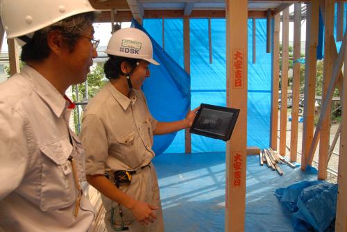 パースをiPad（アイパッド）に取り込み、完成イメージを現場で大工に説明する。右が成田さん（写真：日経ホームビルダー）