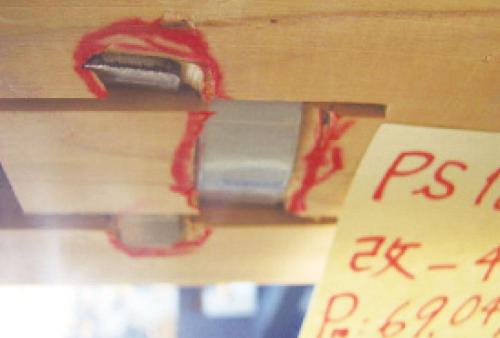 タイプMを取り付けたムクの梁の破壊形状。つなぎと梁受けが木にめり込んで、梁の割裂を防いだ（写真：カネシン）