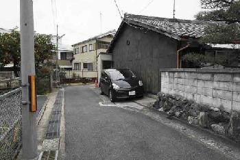 前面の道から敷地を見る（2階建ての住宅の左隣）。京都市は2006年までに、前面の道を2項道路として6区画の敷地で合計7回、建築確認を下ろしていた（写真：日経アーキテクチュア）